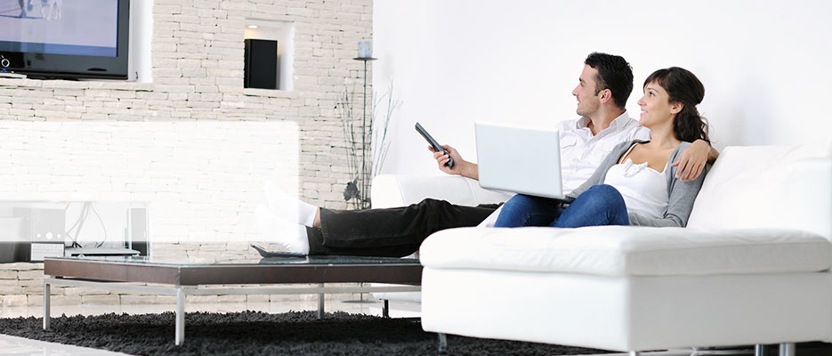 Pareja en un sofá, viendo la televisión en su hogar